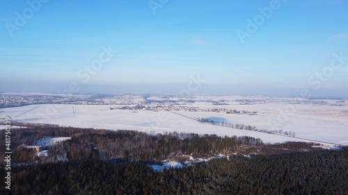 Top view of a winter landscape with a snowy field and a forest