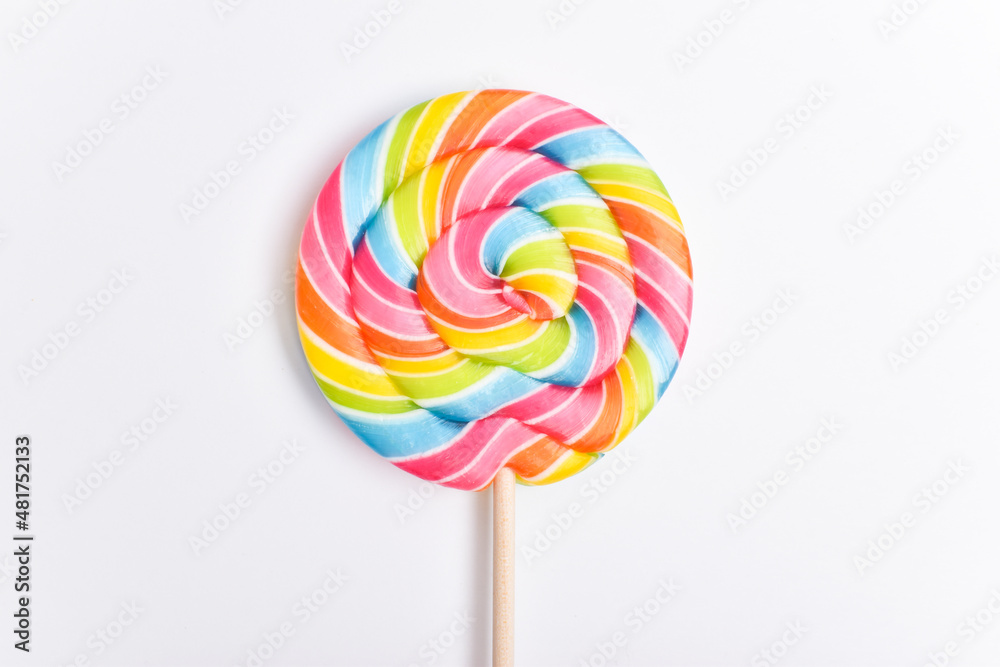 A colored lollipop on a stick. Sweet dessert. Confectionery background. Copy space. Flat lay, top view A colored lollipop on a stick. Sweet dessert. Confectionery background. Copy space. Flat lay, top view