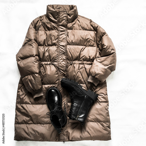 Women's lightweight demi season down jacket and black leather boots on a light background, top view