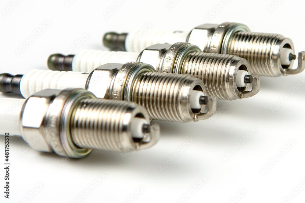 Car service. A set of new car spark plugs as a spare part of motor vehicles on white. Group of candles for the motor close-up Car service. A set of new car spark plugs as a spare part of motor vehicles on white. Group of candles for the motor close-up