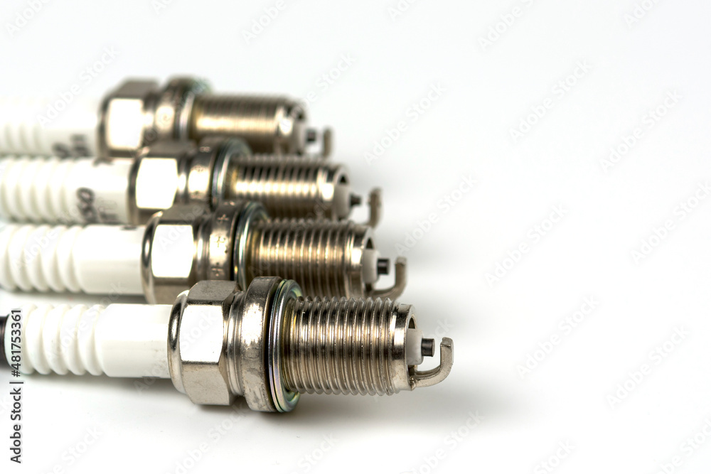 New spark plug on a white background, isolated. Group of four spark plugs for an automobile motor close-up. copy space New spark plug on a white background, isolated. Group of four spark plugs for an automobile motor close-up. copy space