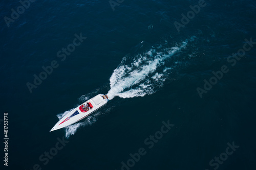 Big white boat with people in motion on the sea. Boat performance drone view. Performance speedboat moving fast on blue water aerial view.