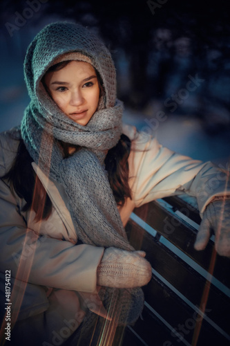 Obraz na płótnie Portrait of a young woman on a bench in a night winter park w salonie