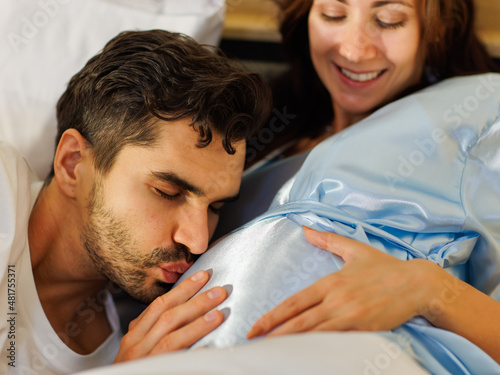 Lovely father close eyes and tenderly kiss and touch beloved belly to cherish unborn baby with hopeful dream of happy family