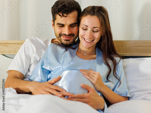 Cheerful husband enjoy embracing pregnant wife and happy to tenderly fondle beloved belly of unborn baby and expecting warm family during prenatal care of maternity at romantic bedroom © Bangkok Click Studio