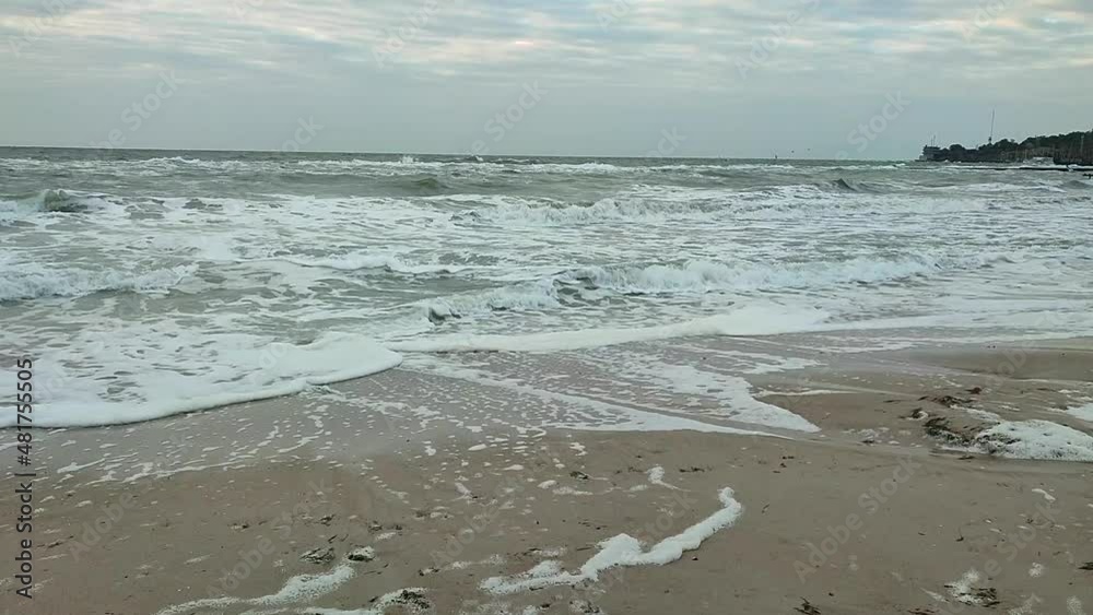 Landscape sea waves white foam storm wind blue sky skyline flying seagulls on sunny day. Sandy beach shore sea coast seashore in city Landscape sea waves white foam storm wind blue sky skyline flying seagulls on sunny day. Sandy beach shore sea coast seashore in city