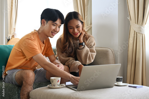 Young couple sitting in living room and shopping online with computer laptop.