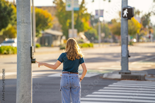 A young woman pressing the button to cross the road. 