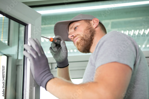 Fotografija male contractor using screwdriver on pvc window
