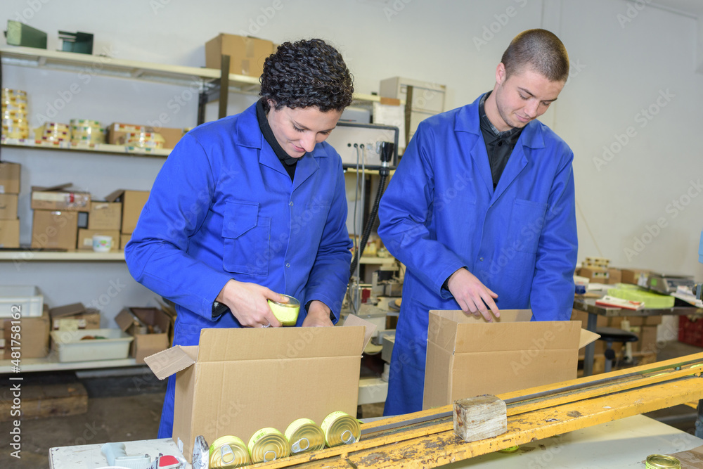 factory workers packing tins into box factory workers packing tins into box
