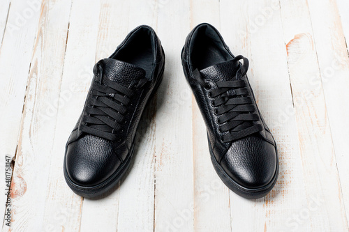 Black imitation leather shoes laced with wide laces. Close-up shot. © Pavlo