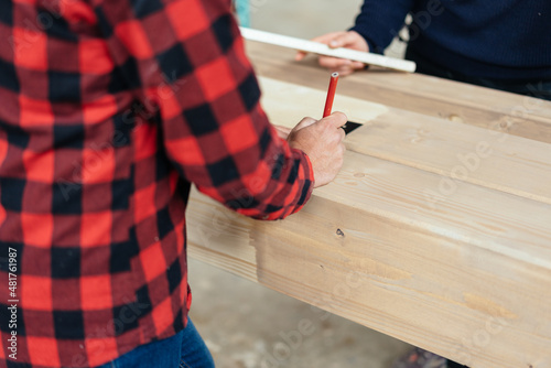 Hand of a factory worker taking measurement on wood