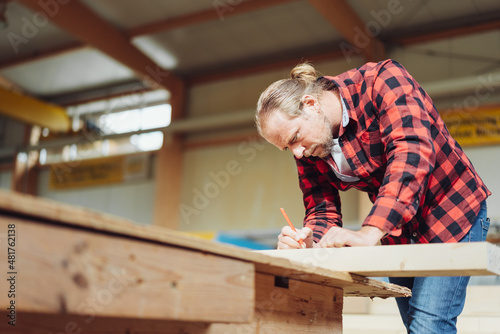 carpenter taking measurement on a large wooden beam
