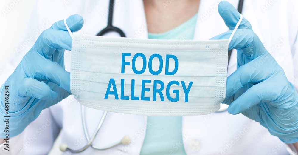 Doctor holds in his hands a protective mask with the text Food Allergy, Medical concept Doctor holds in his hands a protective mask with the text Food Allergy, Medical concept