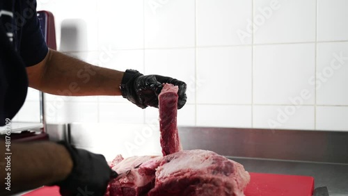 butcher cuts a large piece of selected meat on a steel table