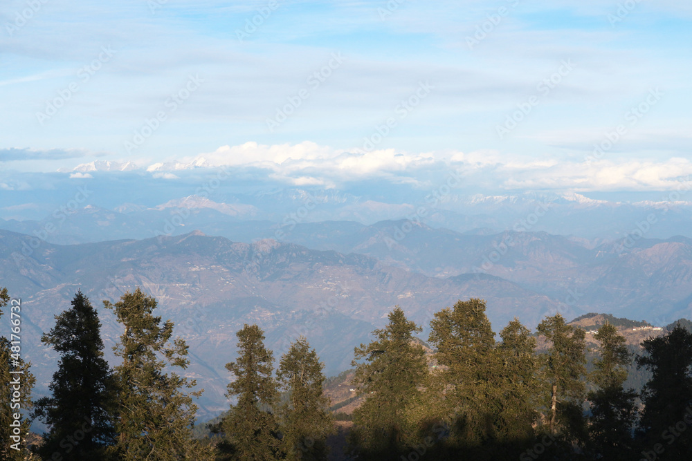 The peaks of the mountains of the Himalayas behind the trees. Natural background - mountain landscape.