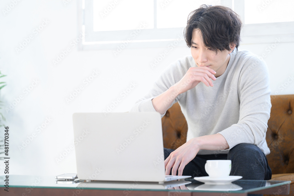 え?これヤバくない?とパソコンを見ながら驚く若い男性 え?これヤバくない?とパソコンを見ながら驚く若い男性
