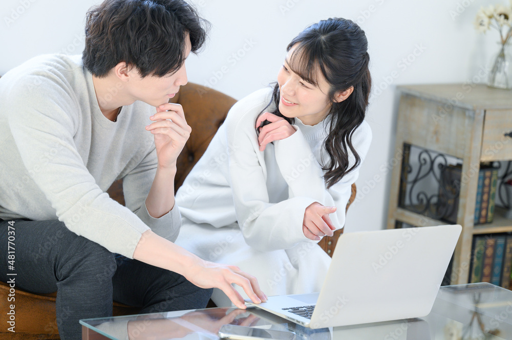 Fototapeta premium A young couple staring at each other while looking for something on the computer together Copy space