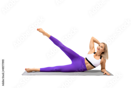 Female workout. Attractive smiling fit woman lying on a mat and does side kicks exercise, isolated on white.
