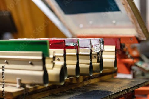 serigraphy production. squeegees on wooden shelve of the print screening apparatus. printing images on t-shirts by silk screen method in a design studio