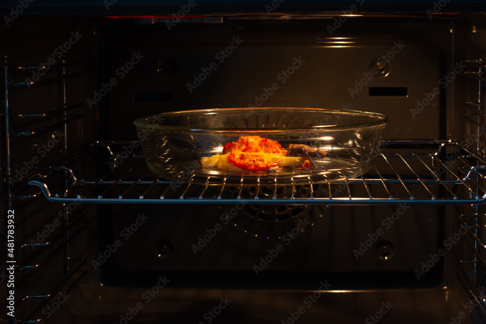 The process of baking marinated meat in a home oven. A few pieces of meat with tomatoes, cheese and spices for roasting meat.