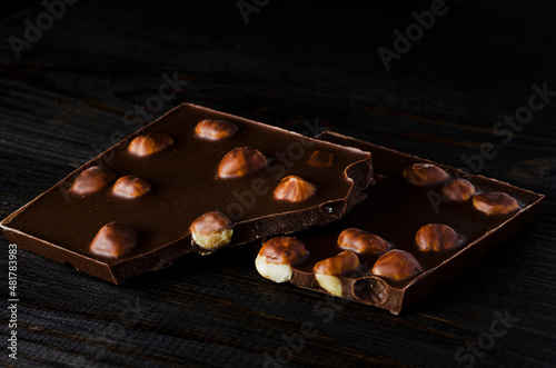 Several appetizing pieces of milk chocolate with nuts on a dark background