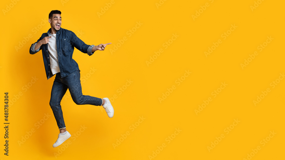 Amazed arab guy jumping up and pointing at copy space Amazed arab guy jumping up and pointing at copy space