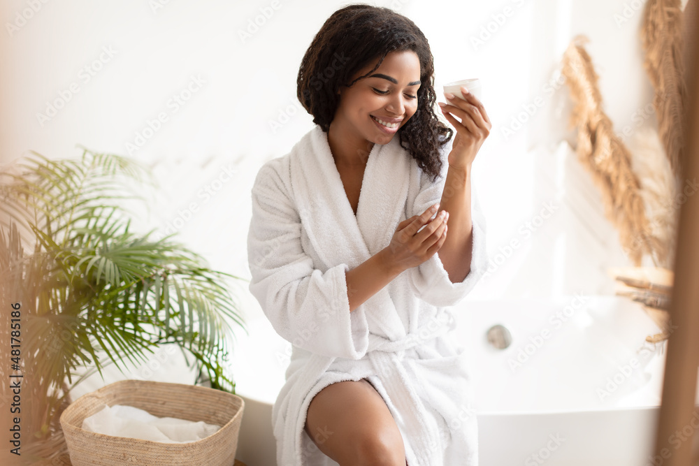 African Woman Moisturizing Body And Hands Applying Cream In Bathroom African Woman Moisturizing Body And Hands Applying Cream In Bathroom
