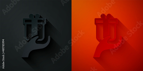Paper cut Give gift icon isolated on black and red background. Gift in hand. The concept of giving and receiving a gift. Paper art style. Vector