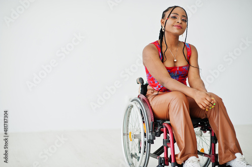 Foto Young disabled African American woman in wheelchair against white wall