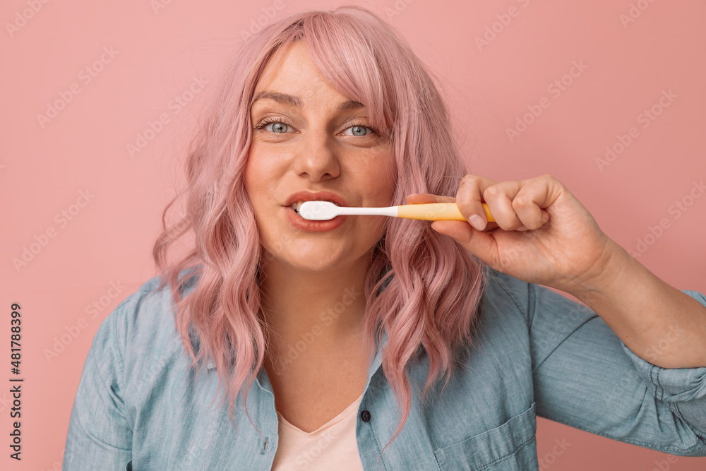 Happy smiling woman brushing healthy teeth with toothbrush, cares of oral hygiene on pink background. Dental care Happy smiling woman brushing healthy teeth with toothbrush, cares of oral hygiene on pink background. Dental care