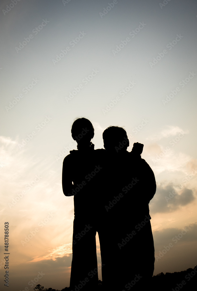 Silhouette of a boy and a girl in-front of evening sky.