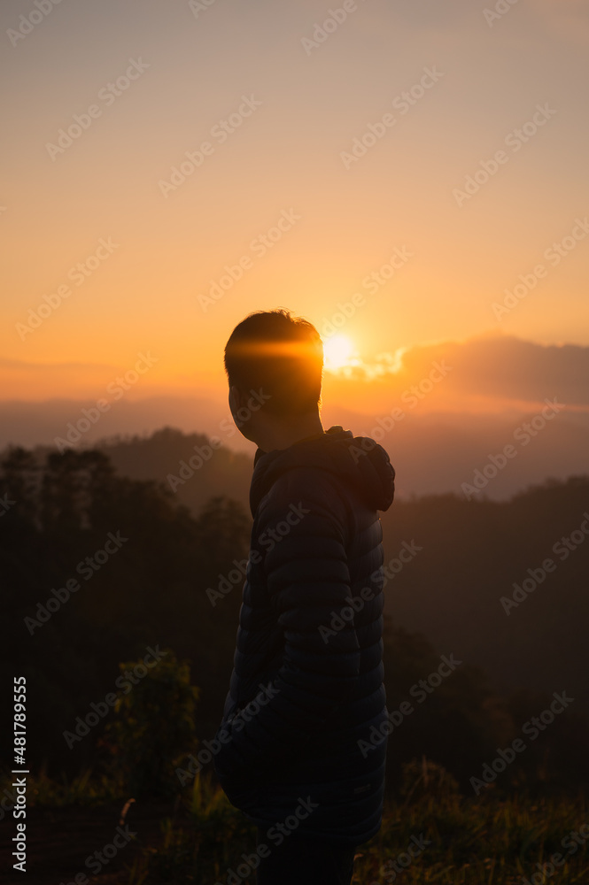 Fototapeta premium Traveler man standing on mountain peak in the sunset
