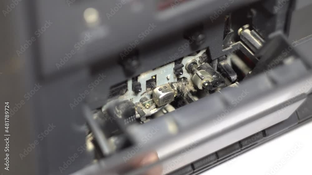 Open cassette deck. Roller rotation. Cassette recorder. Analog control. Dark body. Old tape recorder. Close-up. Fragment of an object Open cassette deck. Roller rotation. Cassette recorder. Analog control. Dark body. Old tape recorder. Close-up. Fragment of an object