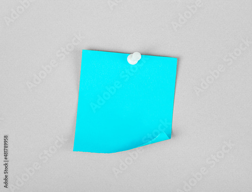 blue small sheet of paper on a button on a gray wall