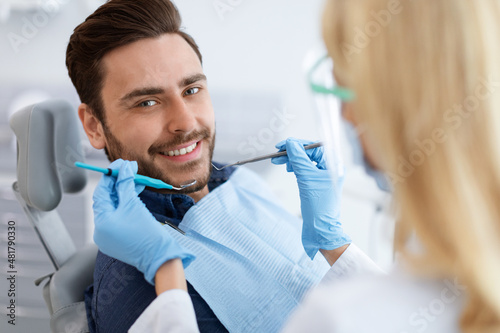 Female dentist doing treatment for cheerful guy