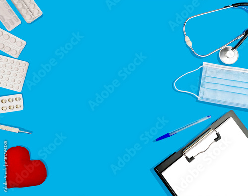 Doctor's table with stethoscope, thermometer, medical mask, pills and red heart, top view, copy space