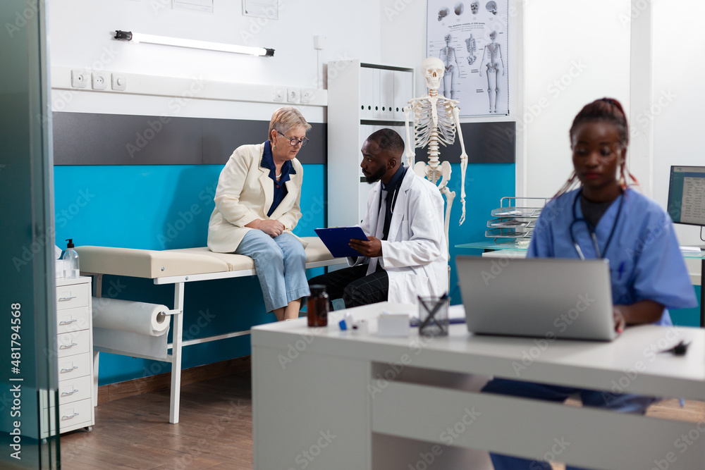 Specialist physician doctor discussing sickness symptoms with senior woman patient explaining healthcare treatment during appointment in hospital office. Doctor writing medical diagnosis on paper Specialist physician doctor discussing sickness symptoms with senior woman patient explaining healthcare treatment during appointment in hospital office. Doctor writing medical diagnosis on paper