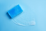 Cleaning blue sponge and a soapy foam on a background. Cleaning concept, cleaning service. Banner. Flat lay, top view