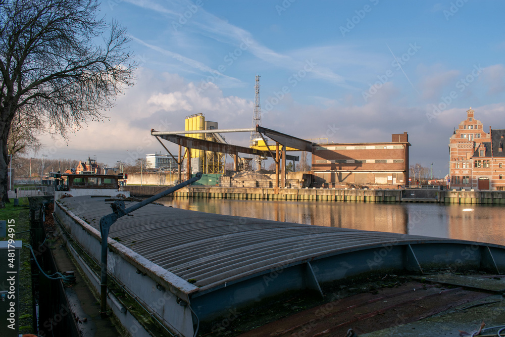 Obraz premium Inland cargo ship with old dock crane in the background. Malines, Belgium
