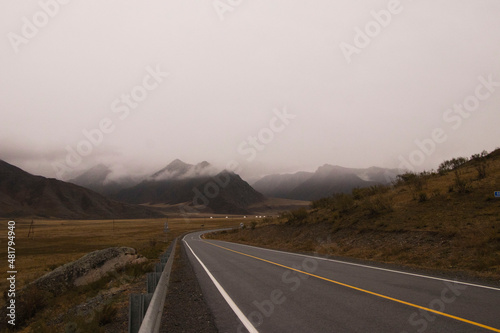 Beautiful road in the mountains, late autumn . The peaks of the mountains are covered with fog. Altai.