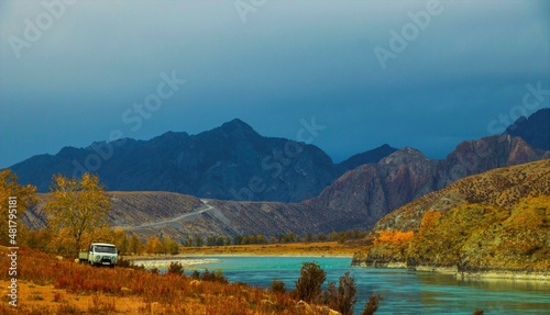 The road in the mountains in autumn. The car descends from the mountain road into a beautiful valley.yellow trees on the bank of a very beautiful river, turquoise, Altai.