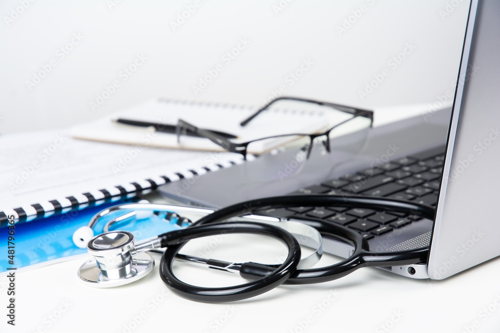 Doctor's workplace, laptop, stethoscope and documents on white table Doctor's workplace, laptop, stethoscope and documents on white table
