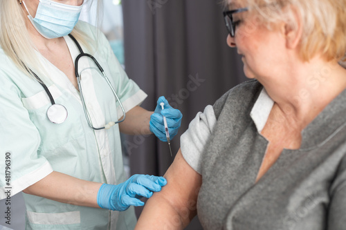 Senior vaccination concept. Elderly getting immune vaccine at arm for flu shot, pneumonia, and shingles in hospital by nurse. Doctor giving an injection to older people patient in clinic photo