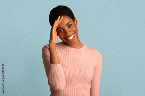 Portrait Of Shy African American Woman Smiling And Touching Head In Embarrassing photo