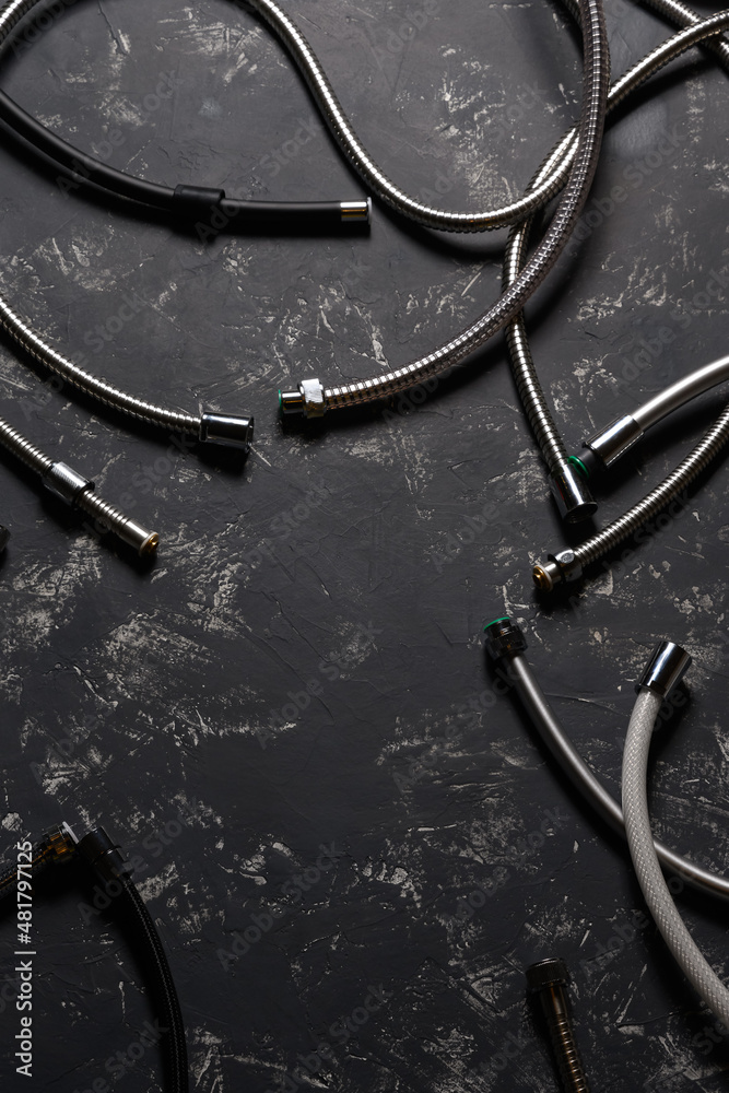 Many different shower hoses on a dark concrete background. Art photography
