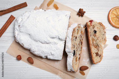 Traditional Christmas Stollen with icing sugar on white wooden table, flat lay