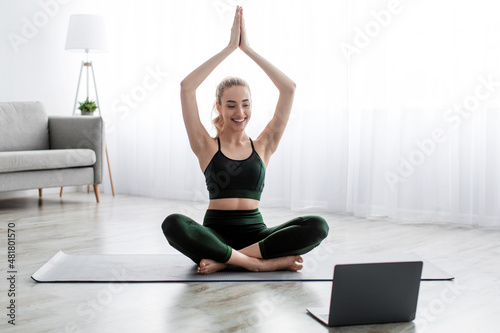 Satisfied caucasian beautiful young blonde woman practicing yoga in lotus position, exercising at home