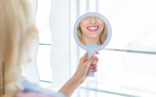 Healthy white smile in hand dental mirror reflection, closeup