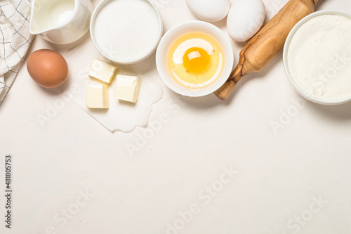 Ingredients for baking at white table. Flour, sugar, eggs and utensils. Top view with copy space.